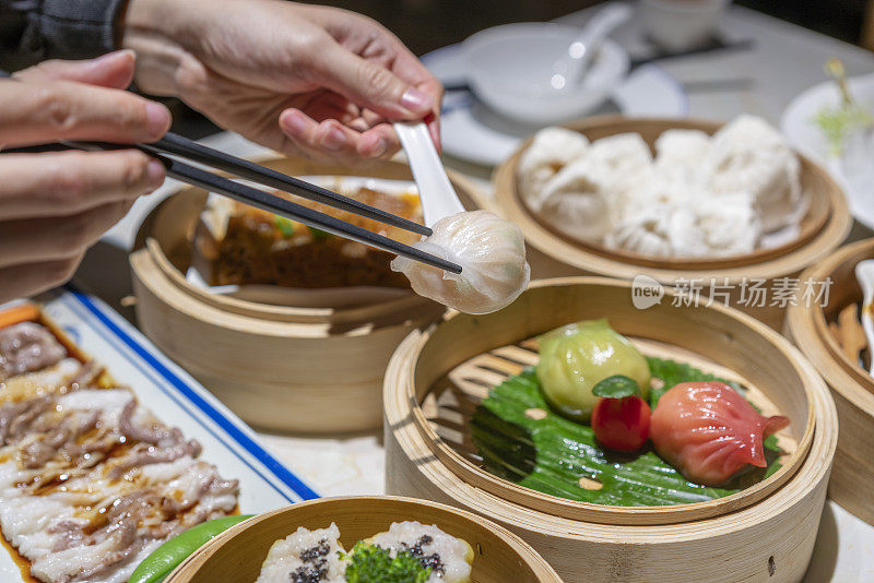 人们用筷子和勺子吃广东dum sum虾饺